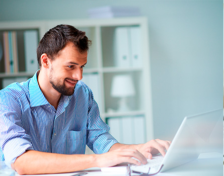 man smiling while using a laptop computer