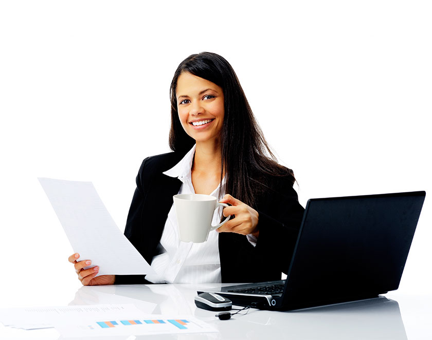 Mujer sonriente tomando café y leyendo un documento con su computadora portátil a un lado