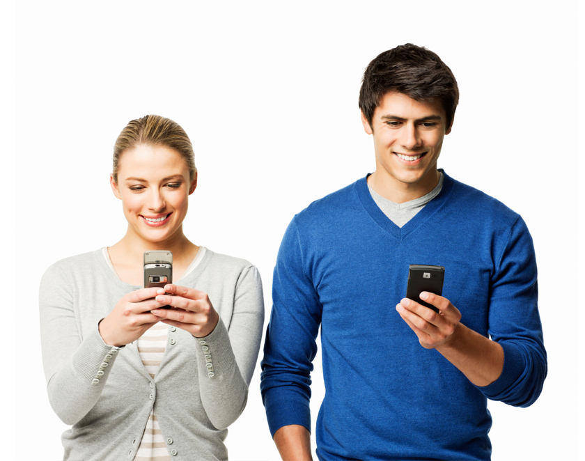 Una pareja de jovenes adultos concentrados en sus dispositivos móviles