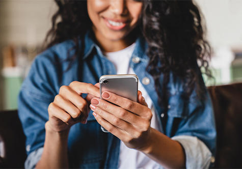 Young adult smiling and using her mobile device