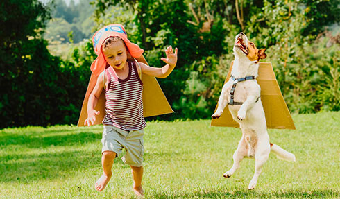 Niño descalzo y su perro jugando en la grama 