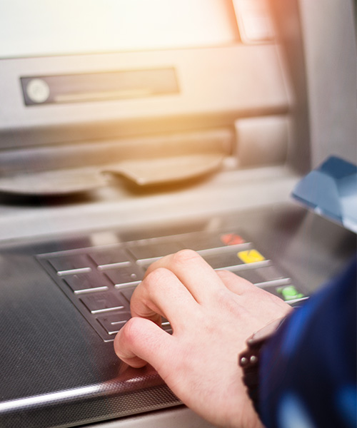 Hand entering its secret pin into a Popular ATM