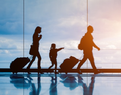 Siluetas de una familia caminando en el aeropuerto con sus maletas 