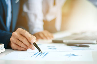 Man hand pointing to graph in document with his pen.
