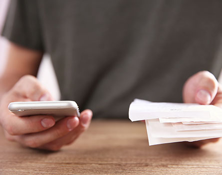 person holding receipts and a cellphone on their hands