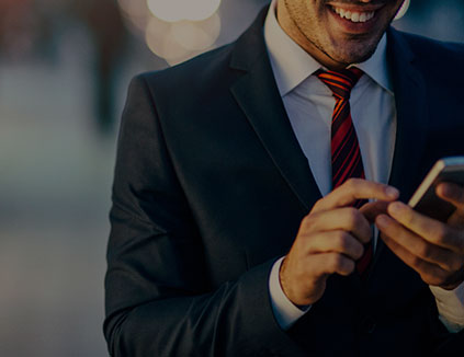 Man in suit smiling and using his mobile device