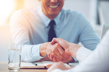 Adult male shaking hands with another person closing a deal