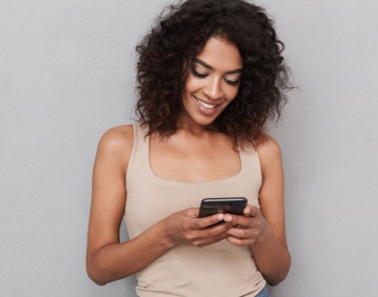Curly hair woman smiling and using her mobile device