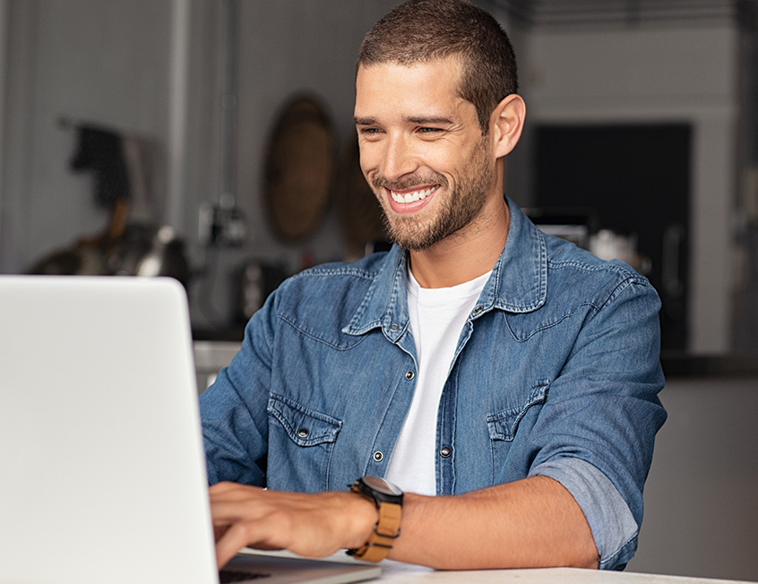 Young adult smiling while using his laptop