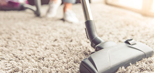 Vacuum cleaner cleaning a cream-colored carpet